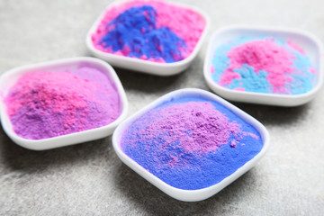 Colorful holi powder in bowls on grey background