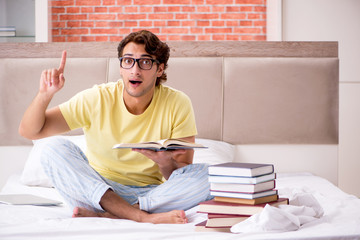 Young student studying in bed for exams