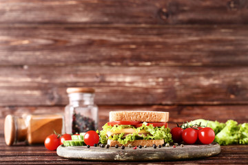 Tasty sandwich with fresh vegetables and pepper spices on brown wooden table