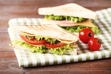 Tasty sandwiches with fresh vegetables on brown wooden table