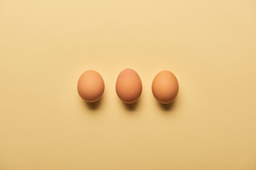 flat lay with brown organic eggs arranged in row on yellow background