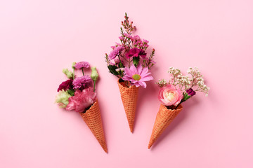 Summer minimal concept. Ice cream cone with pink flowers and leaves on punchy pastel background. Flat lay. Top view. Creative layout