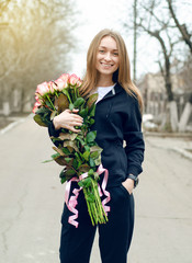 Fototapeta premium Woman with bouquet of pink roses in hand in the street