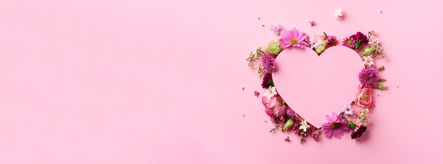 Creative layout with pink flowers, paper heart over punchy pastel background. Top view, flat lay....
