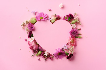 Creative layout with pink flowers, paper heart over punchy pastel background. Top view, flat lay....