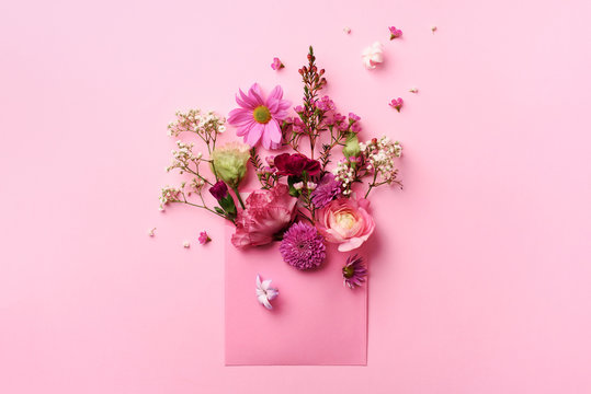 Pink envelope with spring flowers. Floral composition, creative layout. Flat lay, top view. Spring, summer or garden concept. Present for Woman day