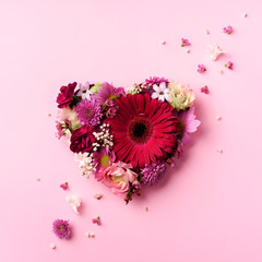 Heart shape made of spring flowers on pink punchy pastel background. Top view, flat lay. Summer...