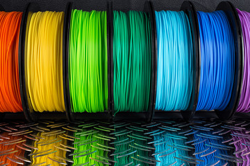 colorful bright  row of spool 3d printer filament black metal background