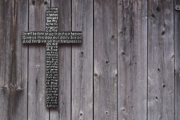 Black wooden cross with the Lord's prayer on the old  dark brown wooden  plank background