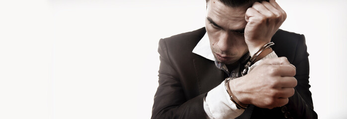 Portrait of handcuffed criminal man imprisoned. Arrest, gangster, pain concept.