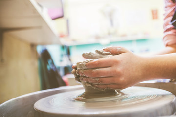 Child hands working with clay on pottery wheel