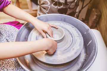 Young potter hands working with clay on pottery wheel