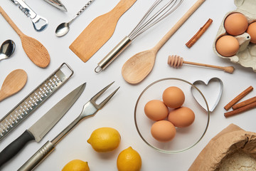 flat lay with metal and wooden cooking utensils and raw products on grey background