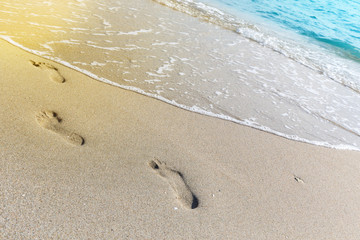 tropical beach, blue sea and white sand with traces of bare feet on it.