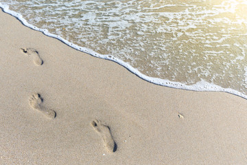 tropical beach, blue sea and white sand with traces of bare feet on it.