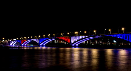 Night lights of the city of Krasnoyarsk. Urban landscape. Reflection of street lighting from the Communal bridge on surface water Yenisei River