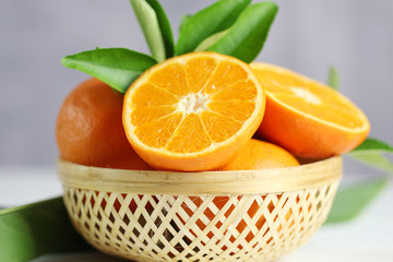 Fresh oranges fruit in basket on white table background.