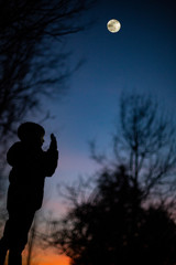 Niño fotografiando la luna a contraluz