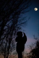 Niño fotografiando la luna a contraluz