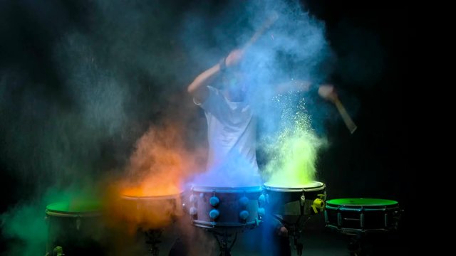 Two young men playing the drum. Colored holi powder