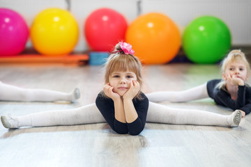 Obraz premium A beautiful child is sitting on the splits in the gym. The concept of sports, education, hobbies, training and dance