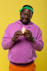 Attentive bearded male person looking at sandwich