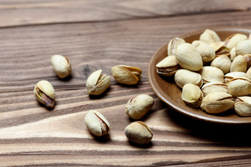 Roasted pistachios on a clay plate. old wood background