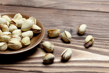 Roasted pistachios on a clay plate. old wood background