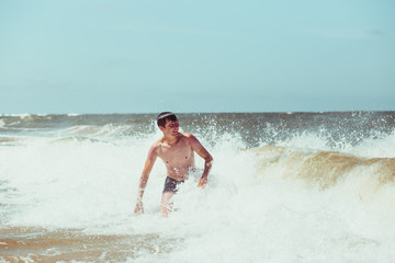 Young man enjoying the high waves in the sea during a summer vacations