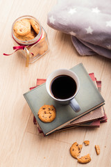 A few books with cup of coffee and cookies on wooden floor