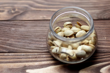 Roasted pistachios in a glass jar. Old wooden background. shallow depth of cut