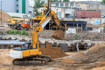 Tracked excavator overloads the sand from the embankment