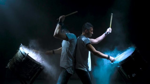 Two young men playing the drum. Colored holi powder
