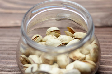 Roasted pistachios in a glass jar. Old wooden background. shallow depth of cut