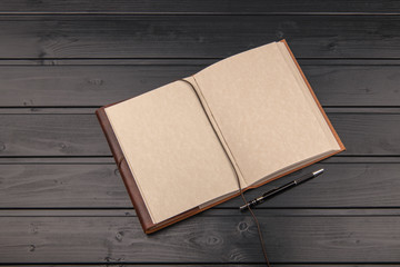 Open notebook with blank pages and pen on the black wooden background