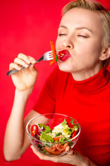 Beautiful caucasian woman eating salad over green natural background	