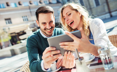 Young couple sitting in the cafe and having fun with tablet. Dating, relationships, love, romance, lifestyle, technology
