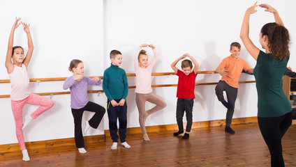 Fototapeta na wymiar industrious boys and girls rehearsing ballet dance in studio