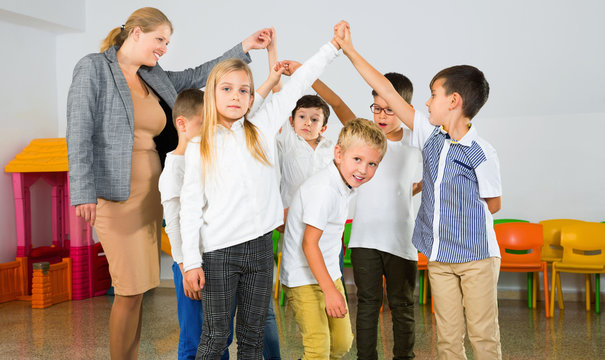 Positive  female teacher playing circle game with children in classrom