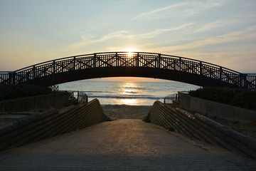 curved wooden bridge to the beach in sunset with sea view, in France