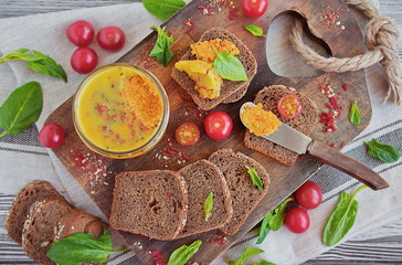 Fresh homemade chicken breast pate in a glass jar. Fresh bread, cherry tomatoes and spinach - specialties to pate on a wooden Board