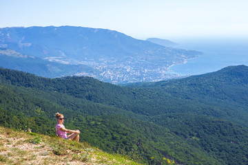 girl sits on a mountain and looks at the sea and mountains