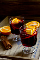 Mulled wine, book, orange and cinnamon on dark wooden background