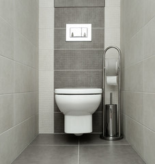 White toilet bowl in modern bathroom with paper holder and toilet brush.