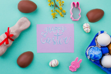 Easter greeting card, eggs and sweets. Chocolate eggs, chicken eggs, styrofoam eggs and chocolate rabbits on colorful background. Easy Easter decor ideas.