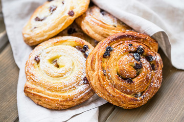 Pastry rolls with raisins and powdered sugar on top, tasty delicious pastry buns freshly baked