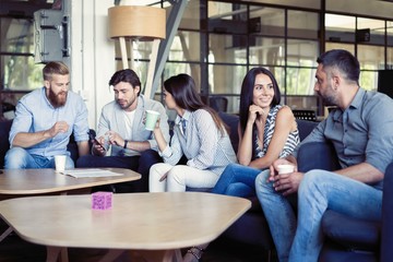Successful young business people are talking and smiling during the coffee break in office.