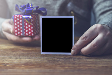 Woman holding black photo stretching it forward with gift