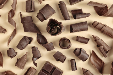 Yummy chocolate curls on color background, top view