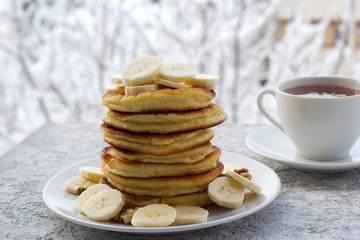 pancakes with honey, banana and nuts, a cup of tea, breakfast, view of the winter landscape